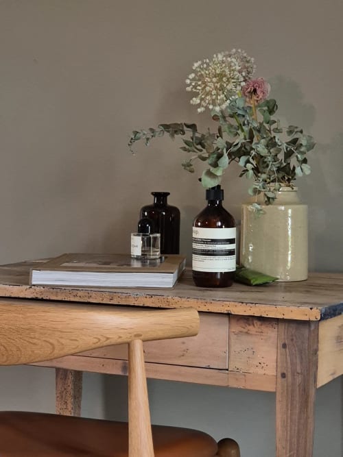 Stijlvol bureau in het Moulin Renaudiots appartement met bloemen, boeken en apothekersflessen tegen beige muur