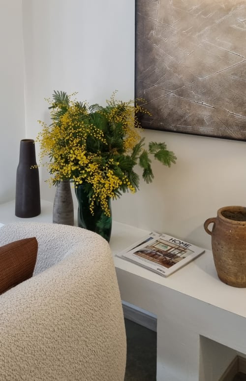 De Saint André kamer in Moulin Renaudiots in Autun beschikt over een zithoek met een crème fauteuil, wit bureau, gele bloemen en donker houtwerk