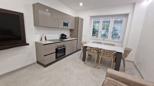 Moderna zona cucina-pranzo nell'appartamento Zoelia Roma con mobili beige, elettrodomestici integrati, tavolo da pranzo e vista sulla città