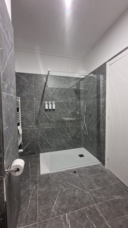 Bagno moderno nell'appartamento Zoelia Roma con doccia in marmo scuro, lavabo bianco e finiture contemporanee