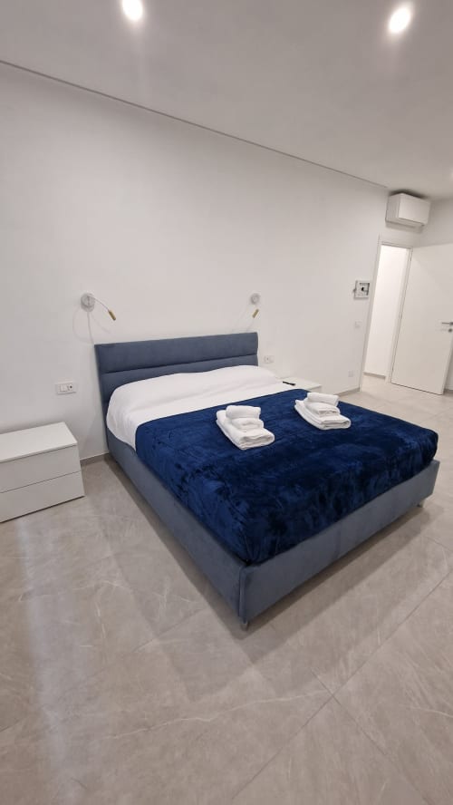 Camera moderna a Zoelia Rome con letto rivestito in blu, biancheria bianca e design minimalista pulito