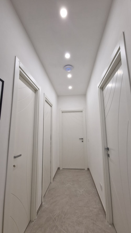 Moderno corridoio con porte bianche e illuminazione incassata presso l'appartamento Zoelia a Roma