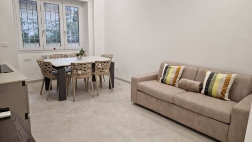 Luminoso appartamento Cipro a Zoelia Roma con divano beige, cuscini rigati, tavolo da pranzo e vista sulla città