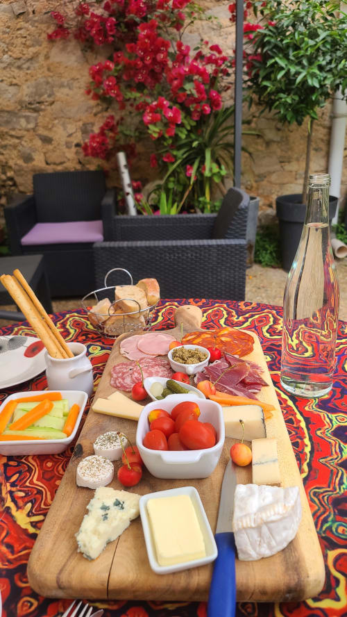 Plateau de charcuterie en terrasse au Le N°9 Argeliers : charcuteries, fromages, tomates fraîches et vin du Minervois sur nappe colorée