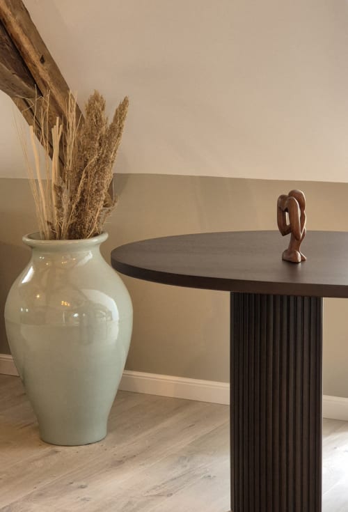 Minimalist hotel interior at Moulin Renaudiots with cream ceramic vase, dried pampas grass, and dark modern table in Autun.