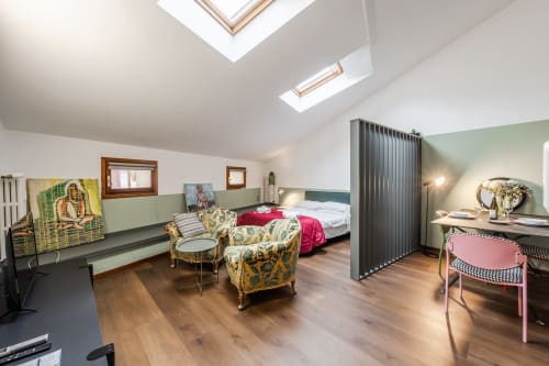 Appartamento Le Arche a Verona con lucernario, poltrone gialle decorate, letto con biancheria rossa e pavimenti in legno