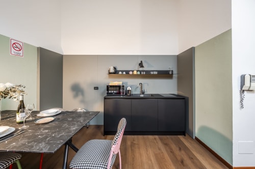 Cucina e zona pranzo moderna di Le Arche Verona con boiserie nera, tavolo in marmo e pavimento in legno