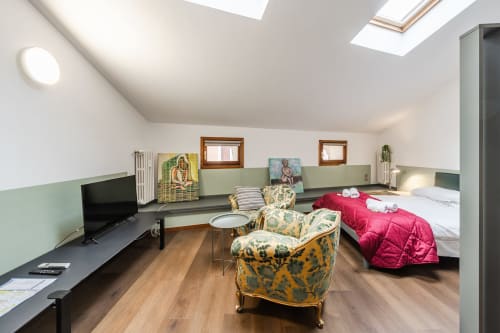 Appartamento Le Arche a Verona con camera da letto in soppalco, poltrone a motivi, TV e vista sulla città da lucernai