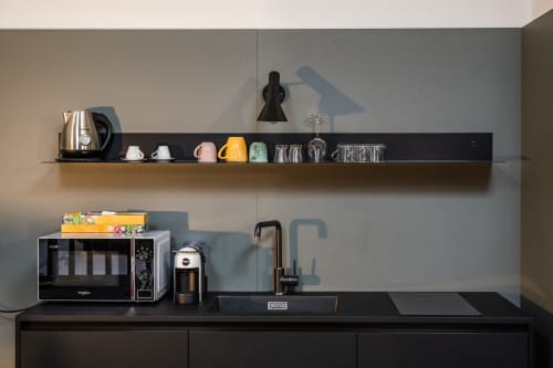 Angolo cottura moderno nell'appartamento Le Arche Verona con scaffali neri, microonde, macchinetta del caffè e vista sulla città