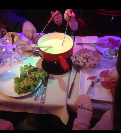 Table de fondue à La Montagnette B&B à Moutiers avec poêlon à fromage, salade et charcuterie