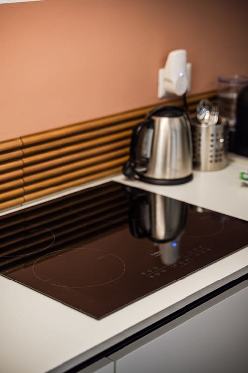 Angolo cucina moderno nell'appartamento Le Arche Verona con piano cottura a induzione, bollitore in acciaio inossidabile e rivestimento in legno