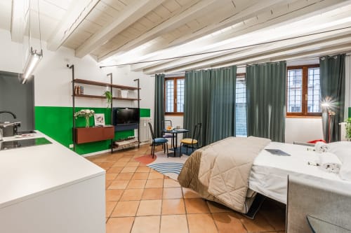 Monolocale Flumen a Le Arche, Verona: studio moderno con parete verde, angolo cottura, letto, scaffalature e vista sulla città