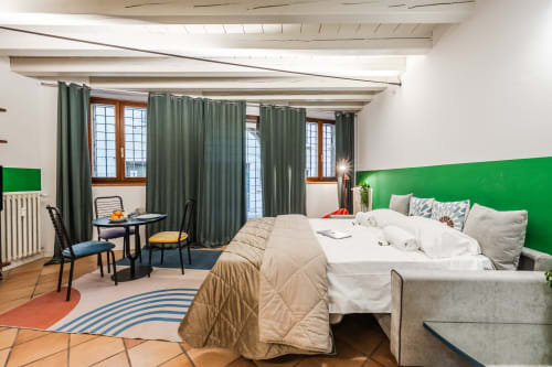 Camera moderna a Le Arche Verona con parete accent verde, vista città e arredamento contemporaneo