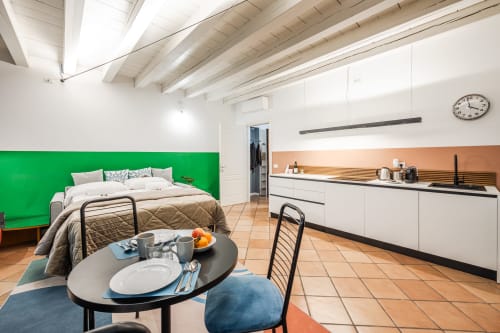 Moderno monolocale Le Arche Verona con parete verde, angolo cottura e zona pranzo con tavolo rotondo
