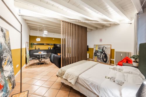 Appartamento Lympha Domus River a Verona con letto, cucina gialla, zona pranzo e divisorio in legno