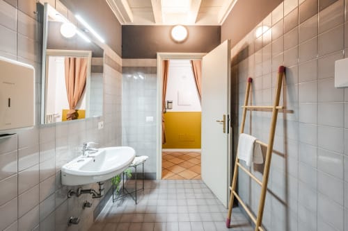 Bagno moderno dell'appartamento Le Arche a Verona con piastrelle bianche, lavabo ovale e scaletta porta-asciugamani in legno