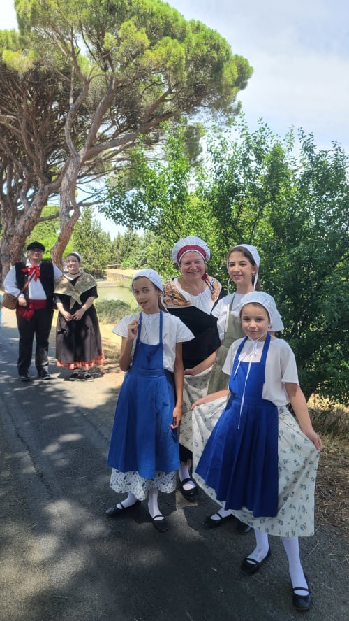 Children in traditional costumes posing under a large umbrella pine tree on the banks of the Canal du Midi near the Le N°9 guest house in Argeliers.