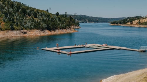 Plataforma flutuante de natação em lago turquesa cercada por colinas florestadas perto de Golegã, Portugal