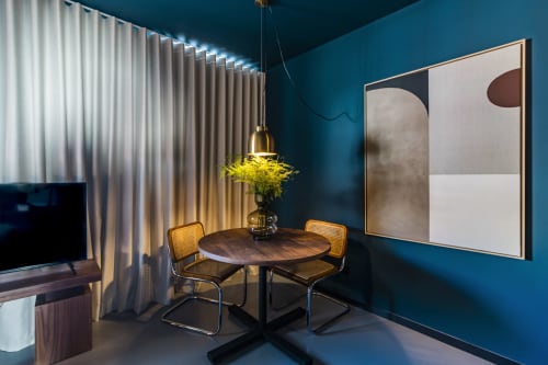 Modern Porto hotel studio with teal walls, round dining table, rattan chairs, pendant lighting, and abstract wall art