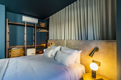 Dormitorio estudio moderno en Benefit Collection Porto con paredes azul verdoso, detalles dorados y mobiliario contemporáneo