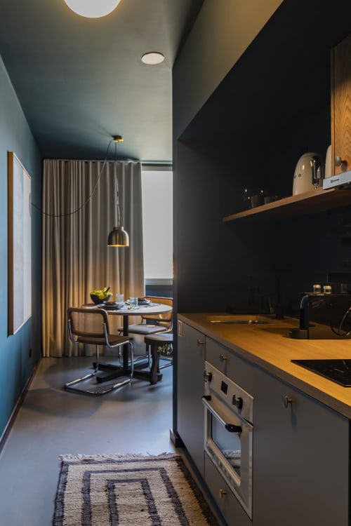 Modern Studio kitchen and dining area in Porto hotel with stove, countertop, and seating by window
