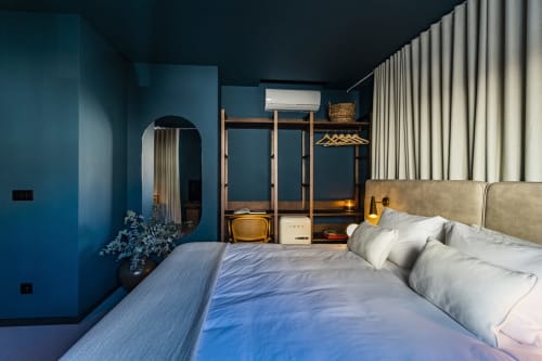 Estudio moderno en Oporto con paredes verde azulado, cama tapizada en beige, armario de madera y luz natural generosa