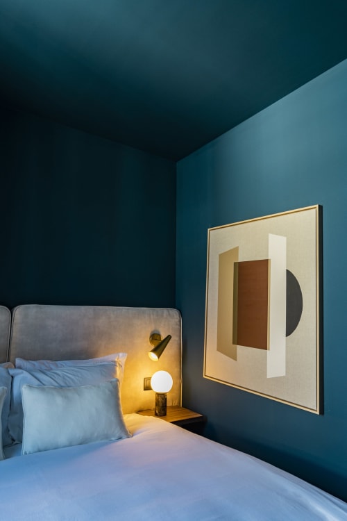 Suite de hotel en Porto con paredes verde azulado, cama con sábanas azules, lámpara de noche y obra de arte abstracta