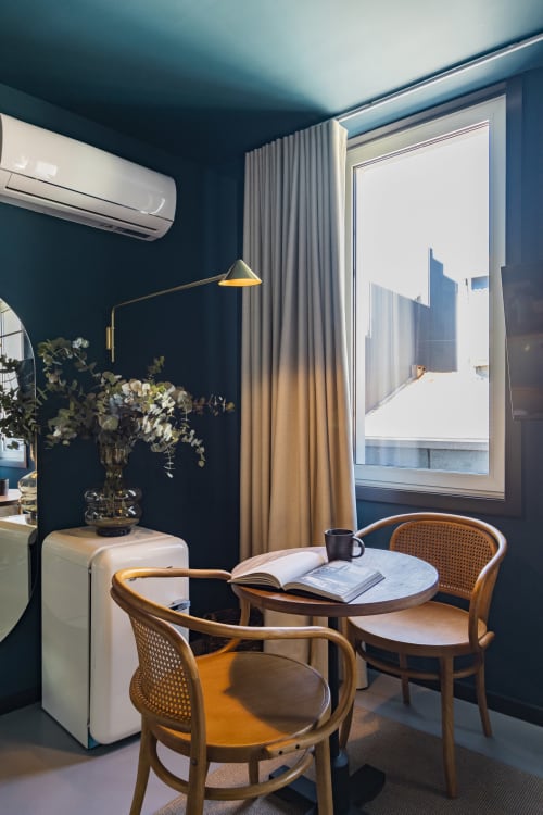 Estudio compacto moderno en Porto con paredes azul verde oscuro, mesa redonda, sillas de madera, vistas a la ciudad