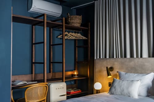 Elegante dormitorio estudio en hotel Porto con paredes azules, armario de madera, zona de trabajo y cama con cabecero de latón