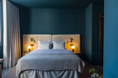 Dormitorio moderno en hotel de Oporto con paredes verde azulado, cama con iluminación cálida en mesitas y vistas a la ciudad