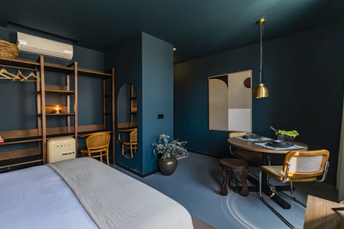Moderno estudio en Porto con paredes color azul teal, muebles de madera, iluminación colgante, área de escritorio y cocina americana en Benefit