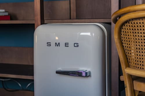Refrigerador SMEG en estudio de hotel en Porto con muebles de madera y silla tejida