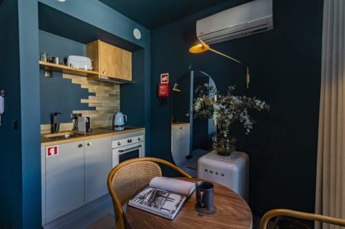 Pequeña cocina moderna con paredes azul verdoso, toques de madera, zona de comedor y frigorífico SMEG en hotel de Oporto