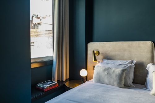 Estudio compacto en Oporto con paredes verde azulado, cama con cabecera gris, vistas a la ciudad e iluminación moderna.