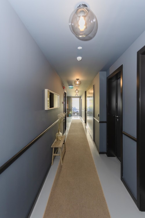 Modern hotel corridor at Benefit Collection Porto with pendant lighting, black doors, and neutral tones