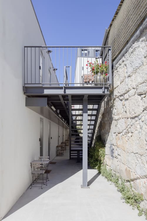 Modern courtyard terrace at Benefit Collection hotel in Porto, featuring metal staircase, white walls, and blooming flowers