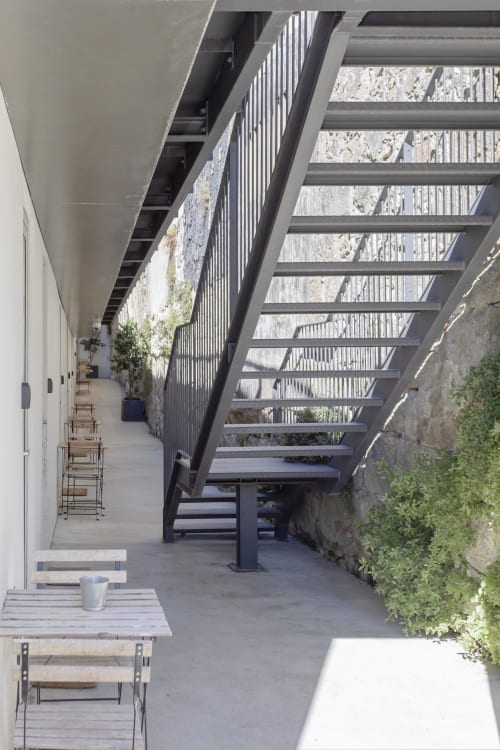 Modern hotel courtyard in Porto with steel pergola, wooden seating, and ivy-covered walls