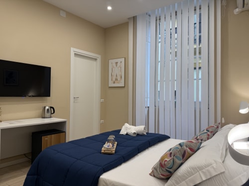Camera moderna all'Encanto Naples con vista città, letto matrimoniale, scrivania, TV e finestre floor-to-ceiling con persiane verticali