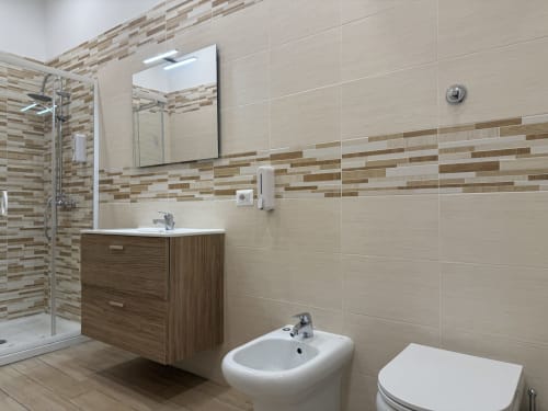 Bagno moderno dell'Encanto Hotel Naples con pareti in piastrelle beige, mobile in legno, bidet e doccia walk-in