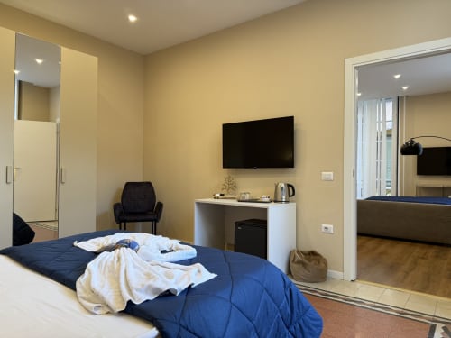 Camera moderna all'Encanto Naples con biancheria blu, TV a parete, scrivania e vista sulla città