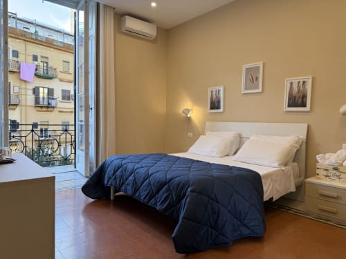 Camera moderna dell'Encanto Hotel Napoli con vista città, piumone blu, biancheria bianca e balcone sulla strada gialla