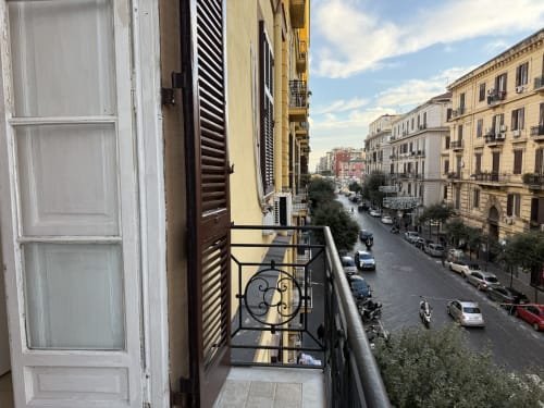 Vista dal balcone della stanza dell'hotel Encanto su una strada di Napoli con edifici storici e traffico cittadino