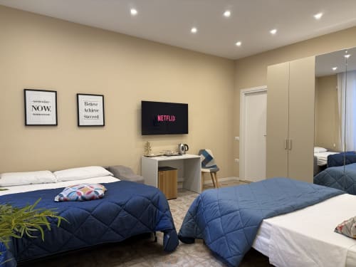 Camera moderna all'Encanto Hotel Naples con letti gemelli, TV Netflix, arte motivazionale e armadio specchiato