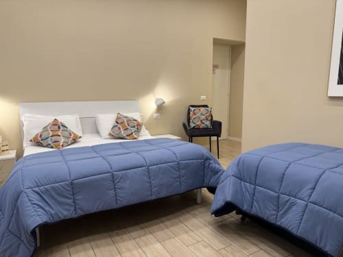 Camera dell'Encanto Hotel Napoli con due letti, coperte blu, cuscini colorati e vista sulla città