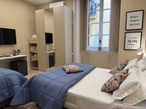 Camera moderna all'Encanto Naples con biancheria blu e bianca, vista città, quadri motivazionali e design compatto