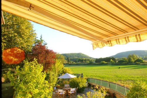 Retracted awning overlooking green valley and mountains at Les Gîtes de l'Impériale, Sermizelles France