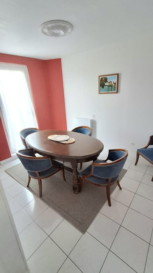 Dining room at Les Gîtes de l'Impériale with oval wooden table, blue chairs, and red accent wall in Sermizelles