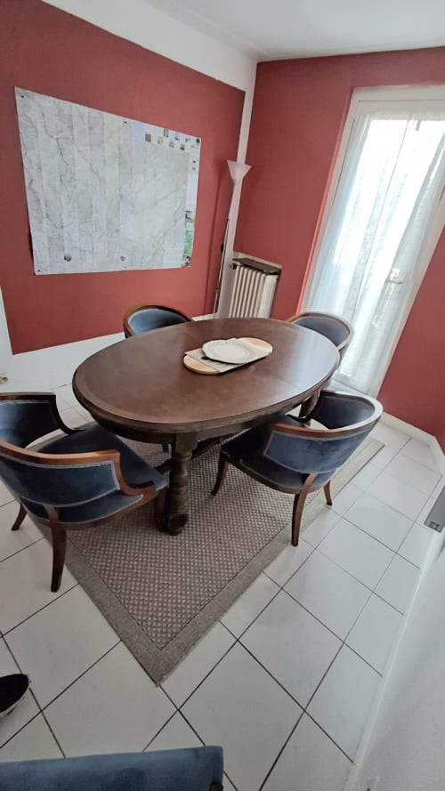 Dining room at Les Gîtes de l'Impériale in Sermizelles with round wooden table and navy chairs on coral walls