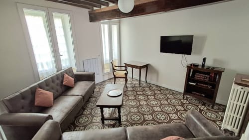 Modern living room at Les Gîtes de l'Impériale in Sermizelles with gray sofa, TV, and patterned tile floor