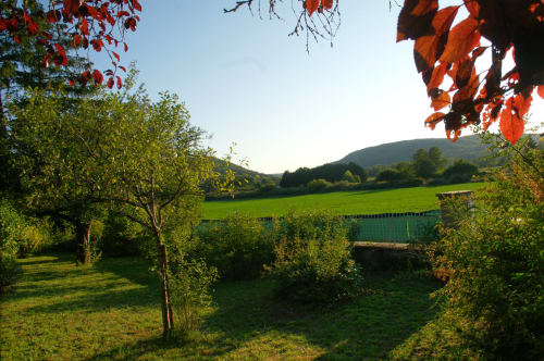 Vue pittoresque du jardin des Gîtes de l'Impériale à Sermizelles avec champs verdoyants, montagnes et feuillages d'automne